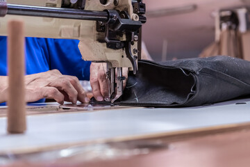 The seamstress sews on an old sewing machine, threads the fabric. Women's hands