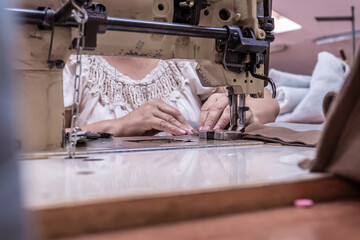 The seamstress sews on an old sewing machine, threads the fabric. Women's hands