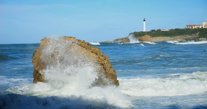 Swell breaking on the beach of Biarritz in the Basque Country with the lighthouse on the horizon (in slow motion)