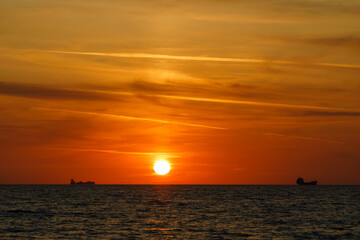 Naklejka na ściany i meble Ships on the horizon at sunset