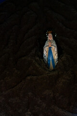 暗い中に浮かび上がる古い教会の中に飾られたマリア像