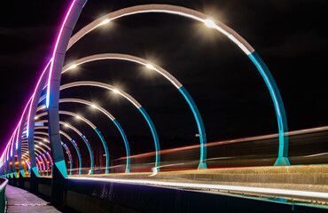 Evening bridge with illumination of different colors across the Tagil River in the Urals. November 2022