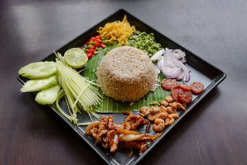 Thai food - Rice mixed with shrimp paste (Kao Cluk Ka Pi) with side dish as a mango, lemon, chili, cucumber, scrambled egg, cow-pea, shallots, Chinese sausage, dried shrimp and pork