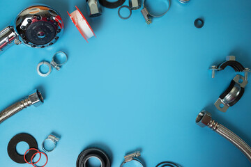 sanitary engineering tools, shower head, hoses, connecting clamps, pipe wrenches and gaskets on a blue background with copy space