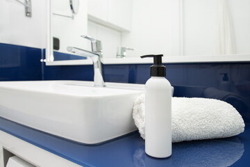 Obraz na płótnie Canvas Sink in the bathroom with dispenser and towel, modern minimalist design in white and blue color