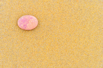 Oval pink sea stone on beach sand. Background. Copy space.