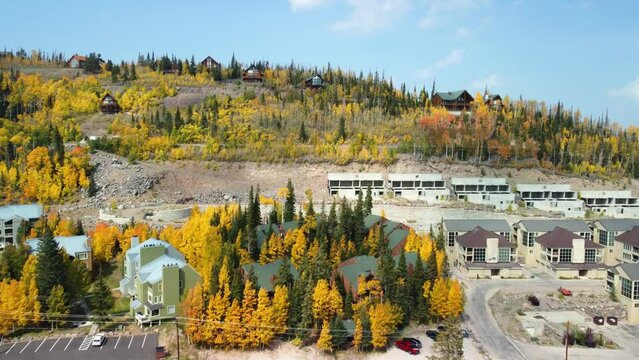 Drone shot of the highway, buildings and tree-covered fields in Brian Head, Utah under a blue sky