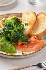 Portion of scrambled eggs breakfast with salmon and avocado