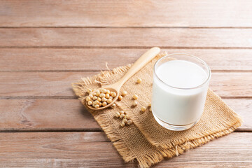 Soy milk in a glass with soybeans on a wooden table Organic breakfast, high protein, healthy, agricultural products, vegetarian