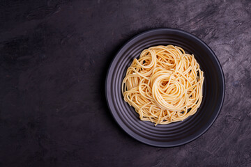 Delicious spaghetti pasta with prawns and cheese served in a black bowl on a black background table Italian recipe, tomato sauce, vegetables, and spices top view with copy space