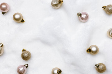 Winter holiday frame, christmas shiny balls on white fake fur. Golden, pale pink color metallic balls, New Year, Happy holidays card, Trend minimal aesthetic background with copy space