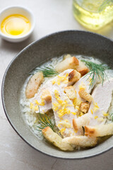 Bowl of soup with chicken breast, white rice, croutons and lemon zest, vertical shot, close-up, selective focus