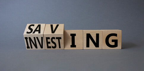 Saving and Investing symbol. Turned wooden cubes with words Investing and Saving. Beautiful grey background. Business and Saving and Investing concept. Copy space