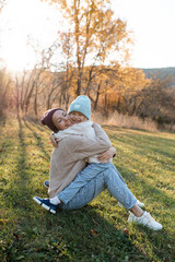 Naklejka na ściany i meble Smiling happy mother holding little baby girl wear casual clothes in autumn park outdoor. Family content. Motherhood.
