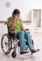 Young male invalid in wheel-chair suffering at home