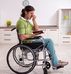 Young male invalid in wheel-chair suffering at home