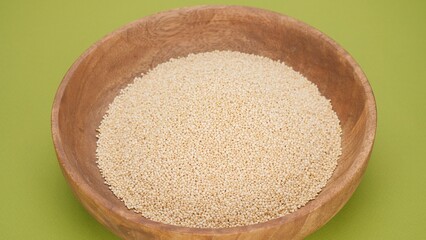 Quinoa seeds superfood in a wooden bowl, isolated on green background