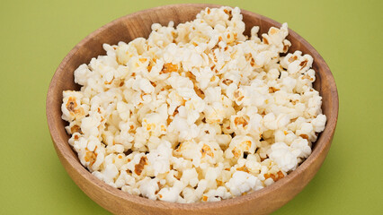 Popcorn in wooden bowl, green background