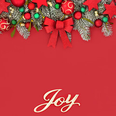 Xmas joy sign for a Happy Christmas concept with tree bauble decorations, bow, fir snow and mistletoe on red. Colorful traditional design for the holiday season.