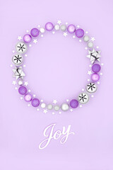 Christmas joy sign with festive wreath and tree bauble ornaments with stars on pastel lilac background. Fantasy abstract concept for winter Xmas and New Year.