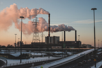 power station at sunset in the big city, with smoke coming out from the chimneys. - obrazy, fototapety, plakaty