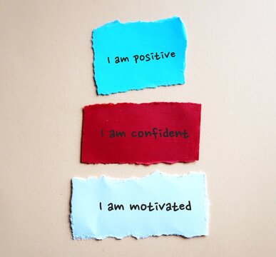 Three torn note on background with handwritten text I AM POSITIVE, I AM CONFIDENT, I AM MOTIVATED - powerful self talk positive affirmations to boost self confidence in daily life