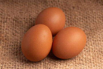 Three fresh chicken eggs on brown background