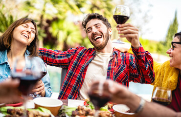 Happy people on genuine mood drinking red wine at pic nic party - Mixed age range friends having...