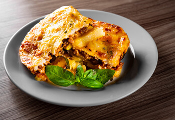 Traditional greek moussaka in white plate on wooden table background