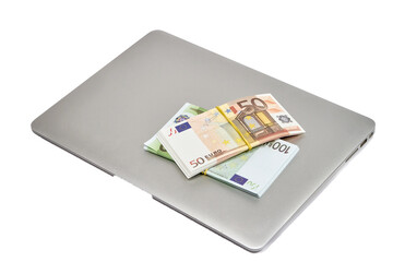 On the computer are stacks of bills of 100 and 50 euros on a white background