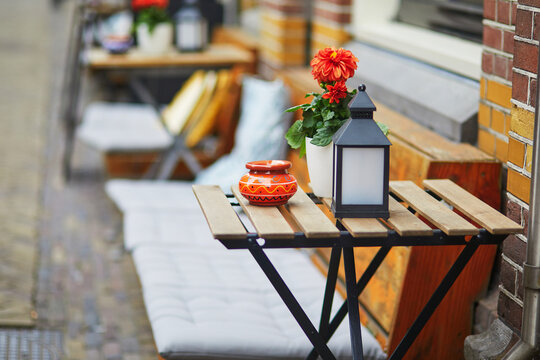 Wooden table decorated with flower pot, candles and lantern in outdoor cafe in Alkmaar