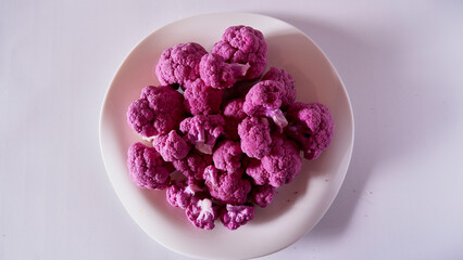 Pieces of purple or pink cauliflower on the white plate, isolated and close up.