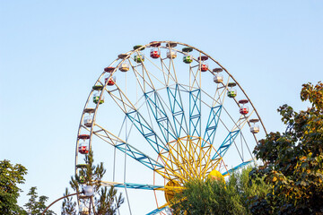 Fototapeta premium High carnival Ferris wheel in the amusement park in summer spinning against the blue sky.