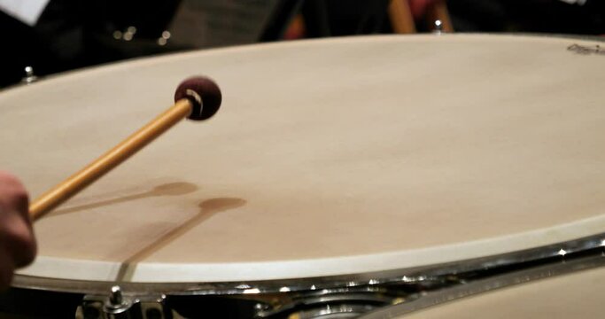 Extreme close up shot of a timpani player drumming with drumsticks during a concert with orchestra for classical music to mozart requiem