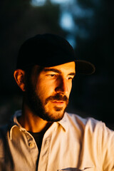 Portrait of a young bearded man, wearing a black cap, at countryside