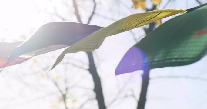 Buddhist pray flags in morning sunlight sky background. Slow motion. 4k footage. Colorful buddhist praying flags waving in sun light. Lens flare. Tibet religion, spiritual, buddha, meditation concept