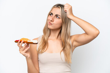 Young caucasian woman holding sashimi isolated on white background having doubts and with confuse...