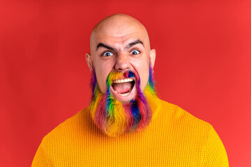 amazed man with long colorful beard feeling excited in red studio background