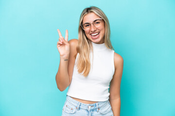 Young caucasian woman isolated on blue background smiling and showing victory sign