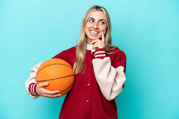 Young caucasian basketball player woman isolated on blue background thinking an idea while looking up