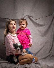 Fototapeta na wymiar A beautiful young mother with a little daughter is photographed in a home studio.