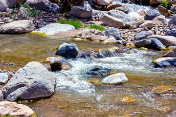Naklejka na ściany i meble Fast mountain river stream water flowing through the rocks close up.
