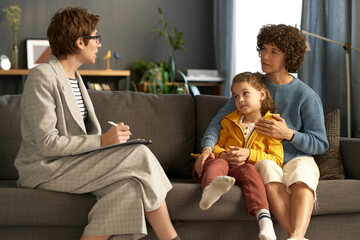 Social worker making notes while talking to adoptive parent and child during their meeting at home