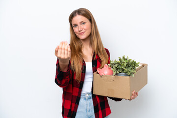 Young caucasian woman making a move while picking up a box full of things isolated on white background inviting to come with hand. Happy that you came