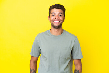 Young handsome Brazilian man isolated on yellow background laughing