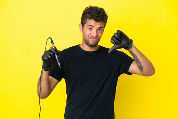 Tattoo artist Brazilian man isolated on yellow background showing thumb down with negative expression