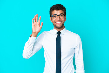 Young business Brazilian man isolated on blue background saluting with hand with happy expression