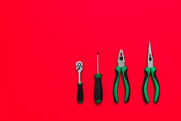 Quality green building pliers and screwdriver tools for repair a car or house on red background. Do...