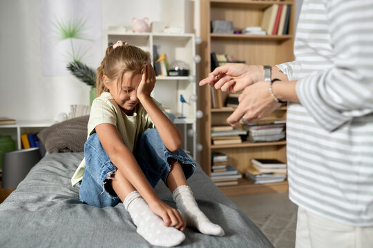 Little Girl Sitting On Her Bed And Crying While Her Mom Scolding Her For Bad Behavior