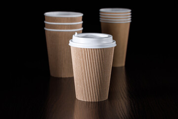 Several disposable paper cups of different types and sizes for drinks on a black background. Side view.